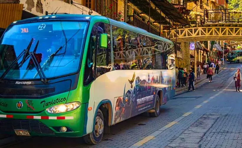 Cómo llegar a Machu Picchu: guía de transporte actualizada - image 2 Bus hacia Machu Picchu. Un bus de transporte turístico en una zona urbana, útil para representar el traslado hacia las estaciones o el acceso por carretera en el viaje a Machu Picchu.